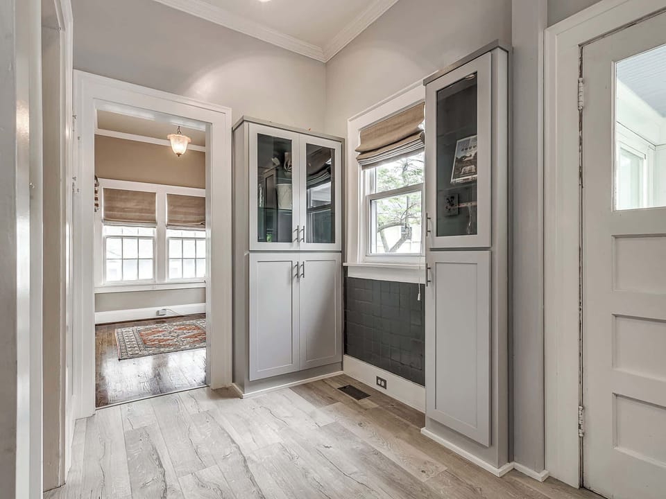 The entryway provides a seamless transition with chic, built-in cabinets for convenient storage, leading to a cozy reading nook or sunroom.