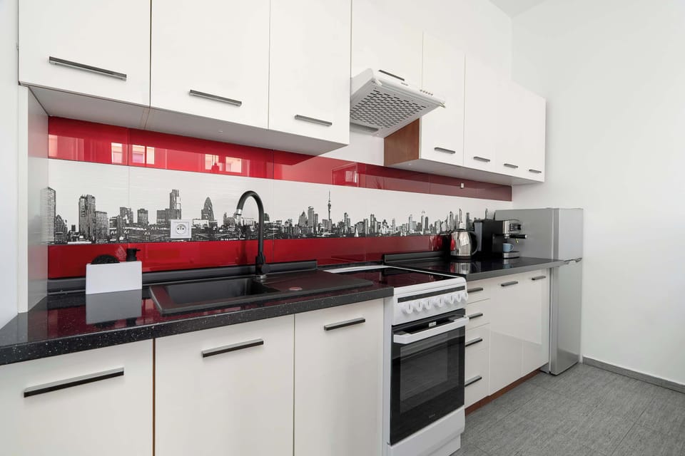 A modern kitchen with white cabinets and a black countertop. It is fully equipped for cooking meals at home.
