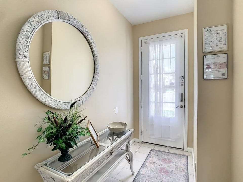 Elegant foyer with a decorative mirror and a touch of greenery to greet you in style.