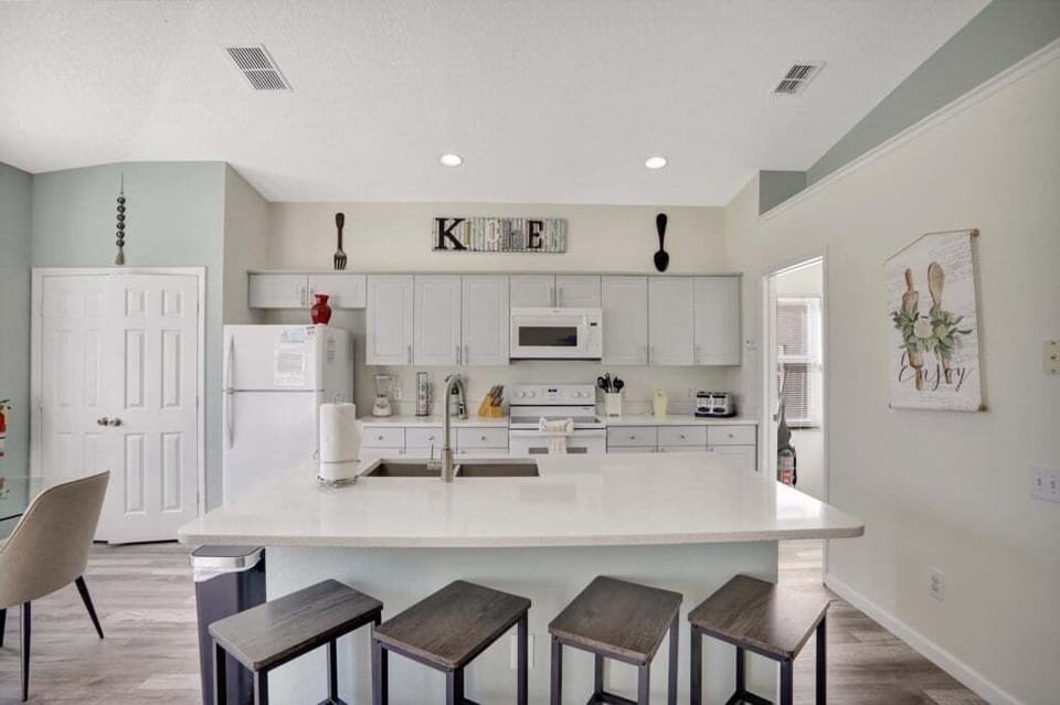 Modern kitchen with bar seating and all essential appliances for a home-cooked meal.