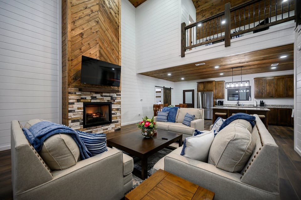 Cozy open-plan cabin with fireplace, loft, and farmhouse kitchen. 