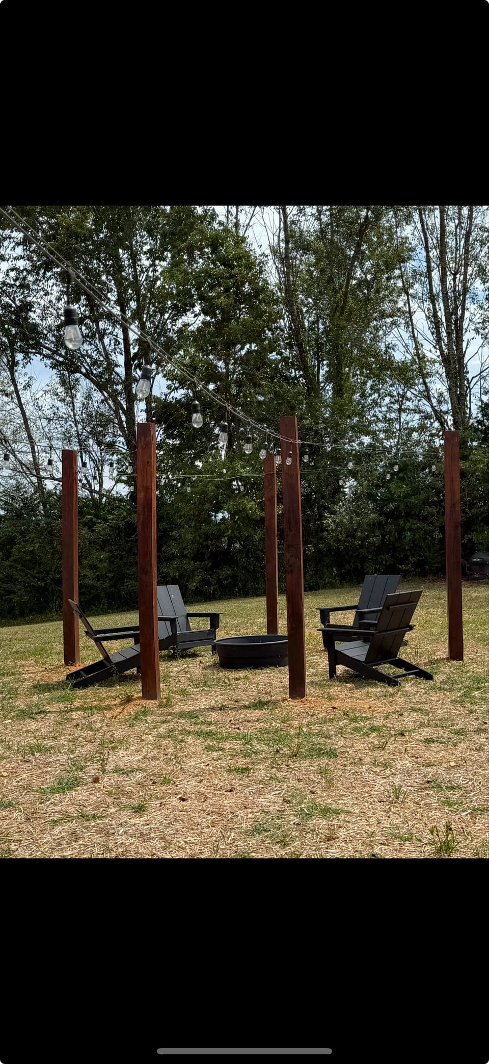 Backyard firepit with 4 chairs and string lights 