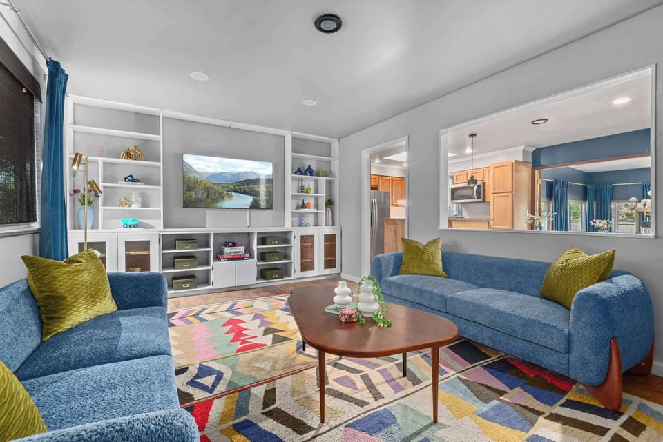 Bright modern living room with blue sofas, large windows, and cozy seating at Westminster Denver Airbnb.