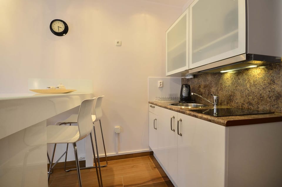 The kitchenette with white furniture is functional and allows for home-cooked meals.