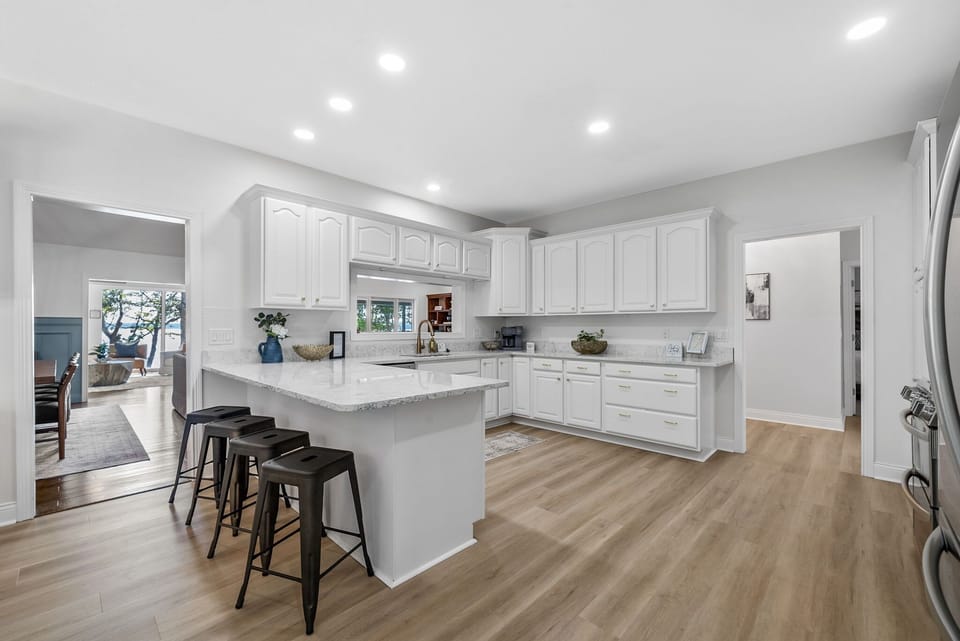 Modern kitchen with white cabinetry, ample light, and large peninsula.