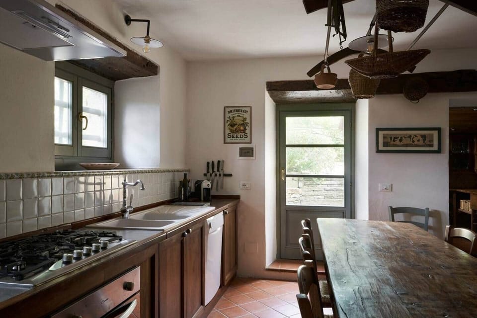 La cucina con uno storico tavolo da pranzo e tutti i comfort moderni: piano cottura, forno elettrico e microonde,  stufa a legna, macchinetta per caffe espresso, caffe americano e tostapane.