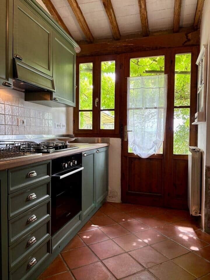 Vista della cucina con accesso diretto al giardino, dove si trova un accogliente tavolo da pranzo all'aperto, perfetto per colazioni al sole o cene sotto le stelle