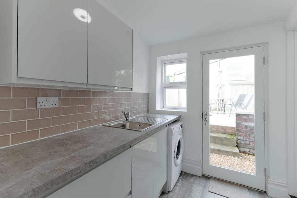 A utility room with a washing machine opens directly into the garden, offering convenience for laundry needs