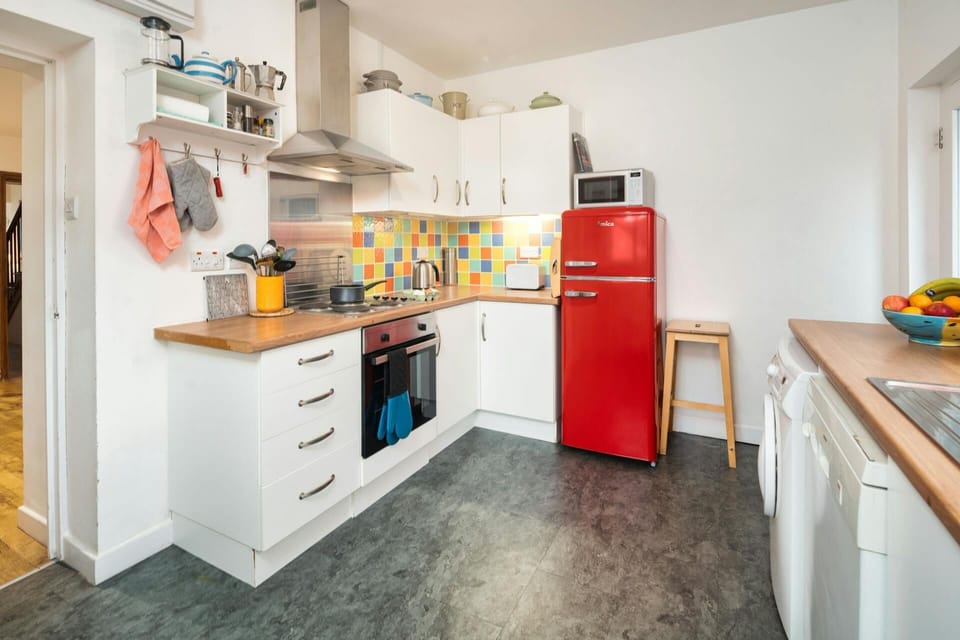 Kitchen with electric oven, hob and extractor hood. Colourful wall tiles