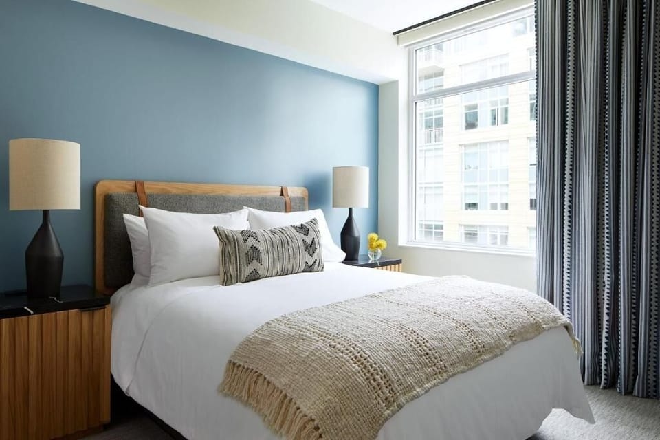 Unwind in crisp linens beside bright city-view windows.