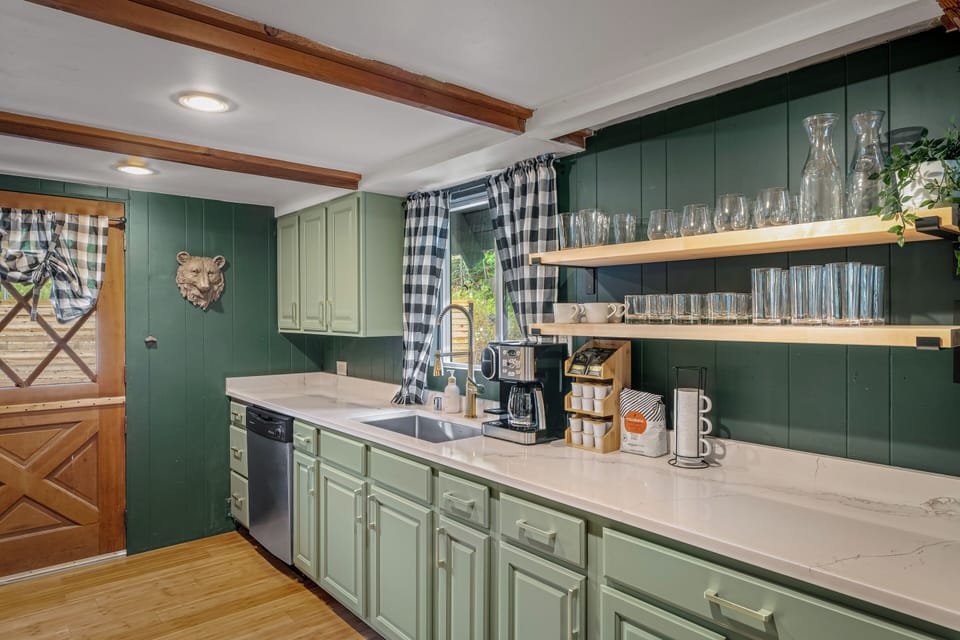 Fully stocked kitchen with coffee maker, glassware, and dishwasher.