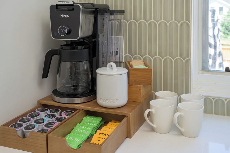 Coffee station with drip coffee maker, mugs, and supplies to start your mornings right.
