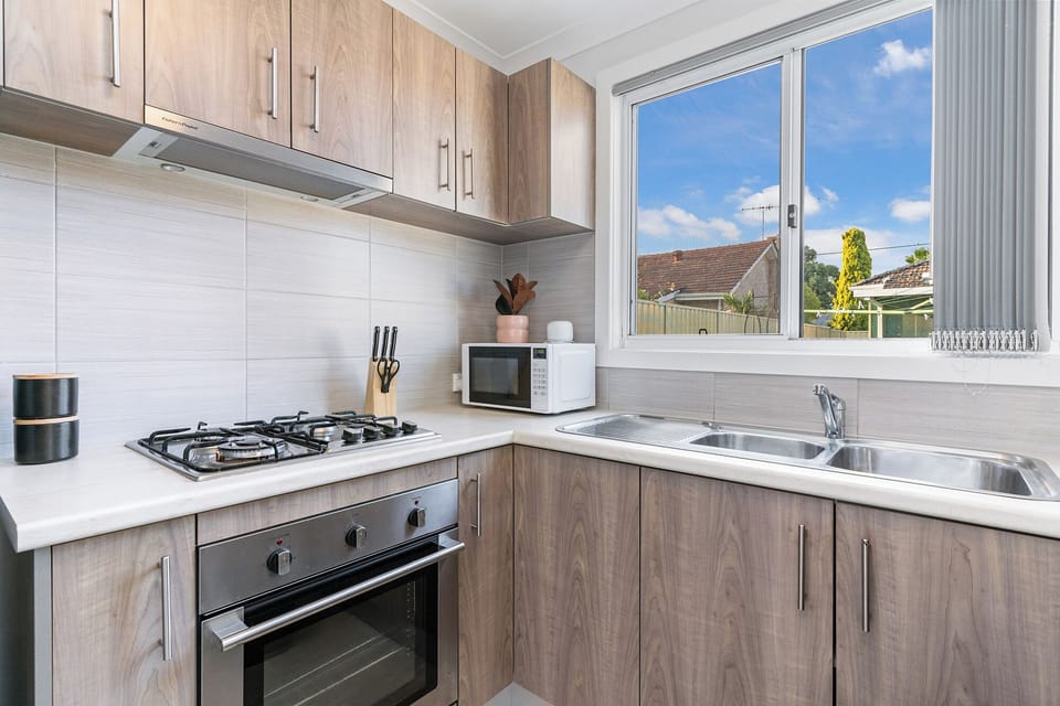 Ready for your culinary creations! This kitchen features a modern gas stove, oven, microwave, and double sink—all the essentials for easy meal prep.
