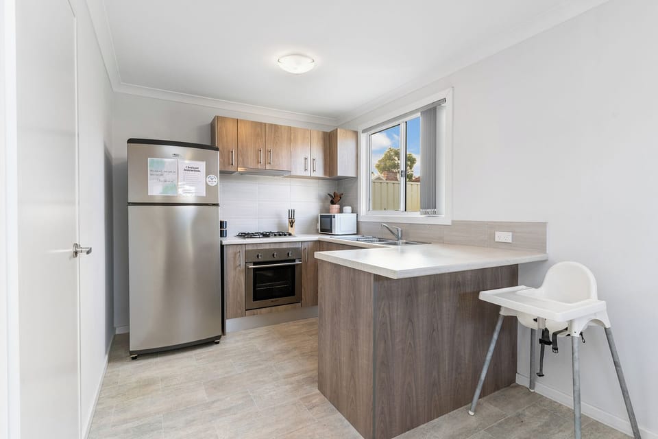 Prepare meals easily in our modern, fully-equipped kitchen. It features sleek stainless steel appliances, ample counter space, and a high chair.