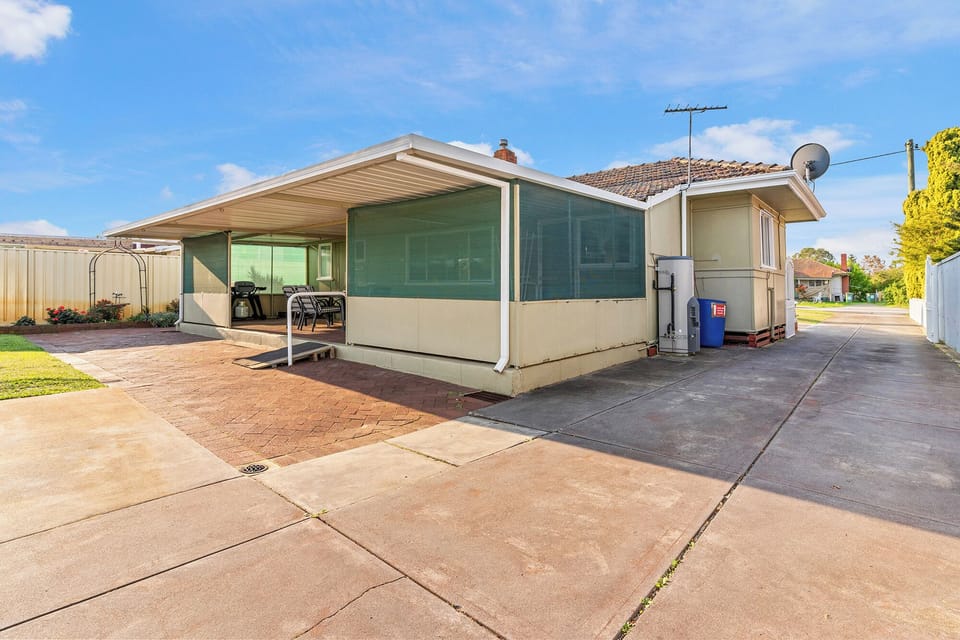 Spacious backyard with a large covered patio and a paved area, perfect for outdoor activities and parking.