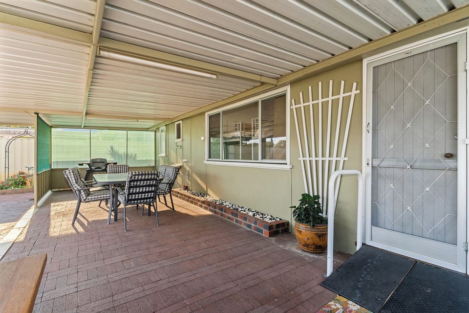 Shaded outdoor patio perfect for a relaxing meal or a casual barbecue, with a comfortable dining set and a grill ready for use.