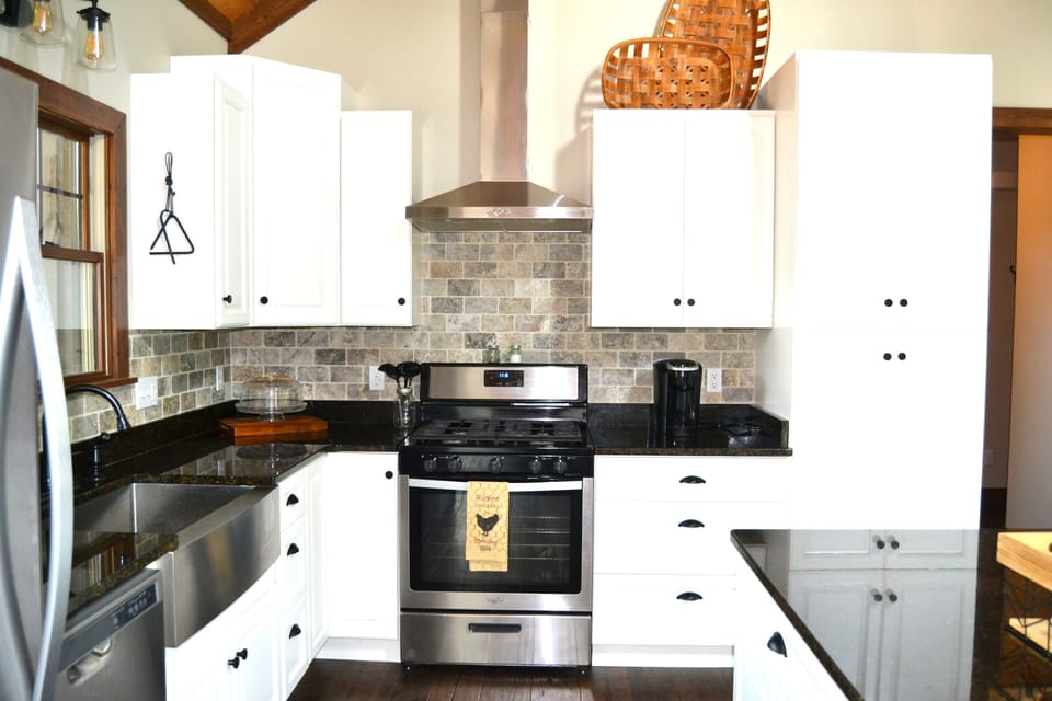 Kitchen with gas stove and stainless range hood.