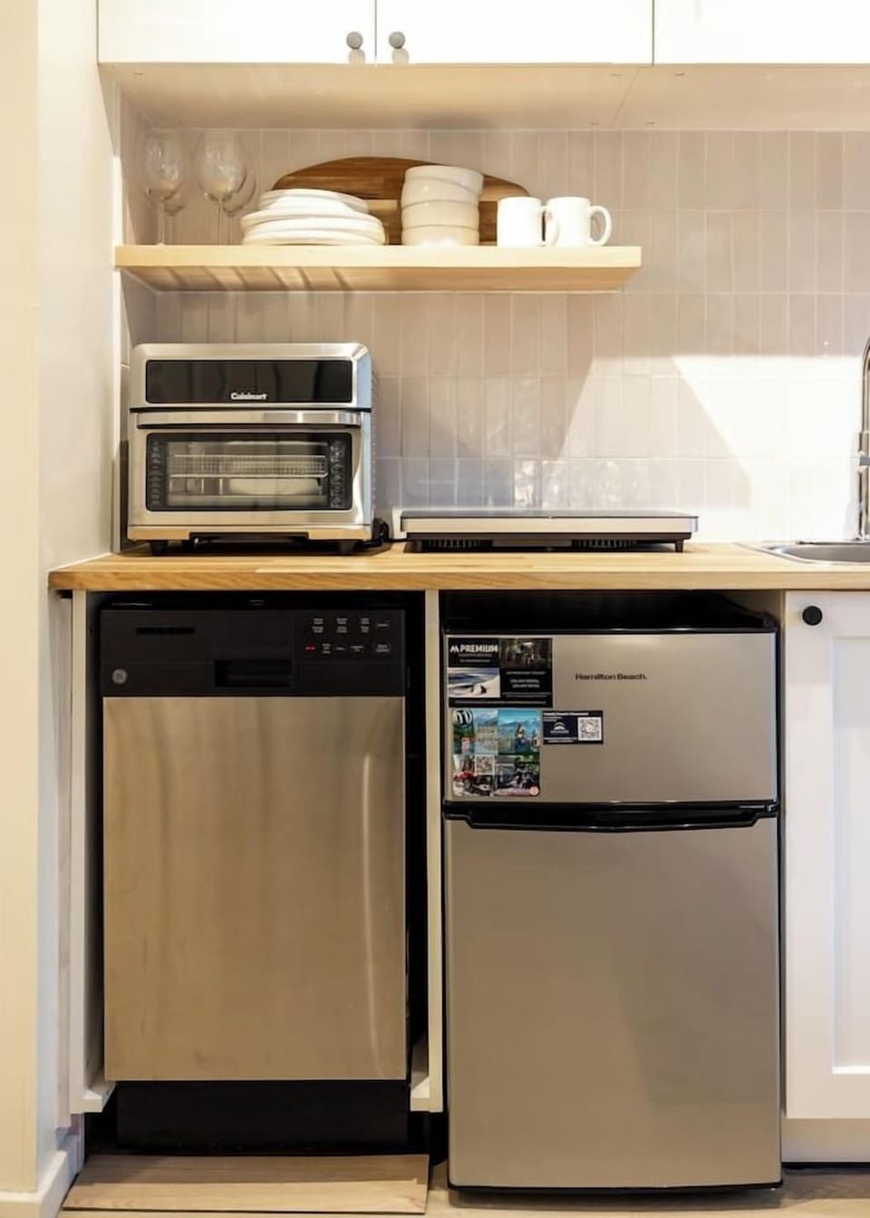 Stylish mini-kitchen stocked with essentials — featuring a compact fridge, dishwasher, hot plate, and air fryer toaster oven, perfect for easy, convenient meals during your stay.