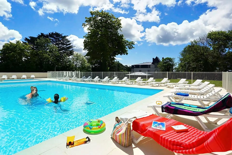 Families enjoy the sun and fun at the outdoor heated pool, surrounded by lounge chairs and lush greenery.