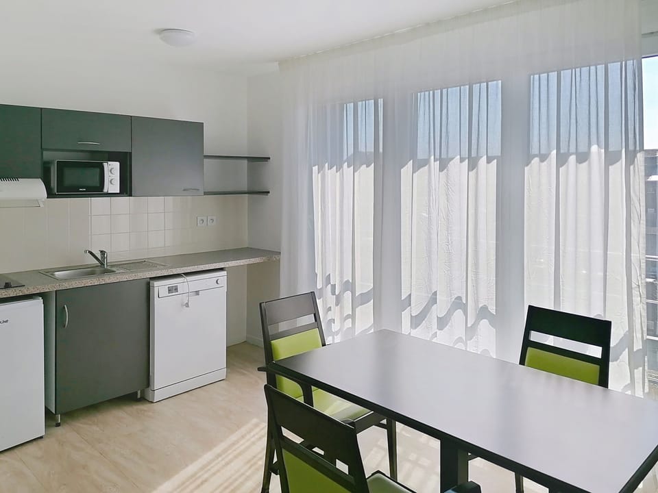 Kitchen with appliances, countertop, and dining table with chairs.