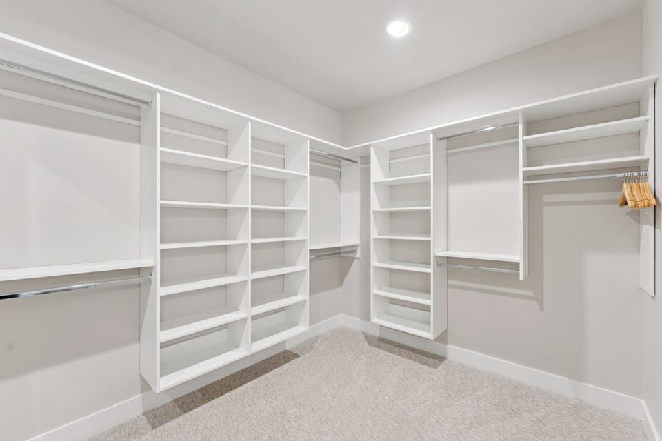Spacious walk-in closet with white shelving and ample storage space.