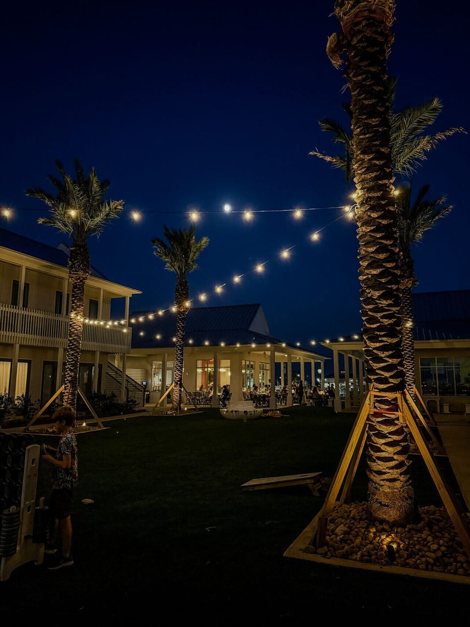 Beautifully lit courtyard featuring coastal architecture, glowing string lights, and inviting outdoor spaces at Field’s Italian.