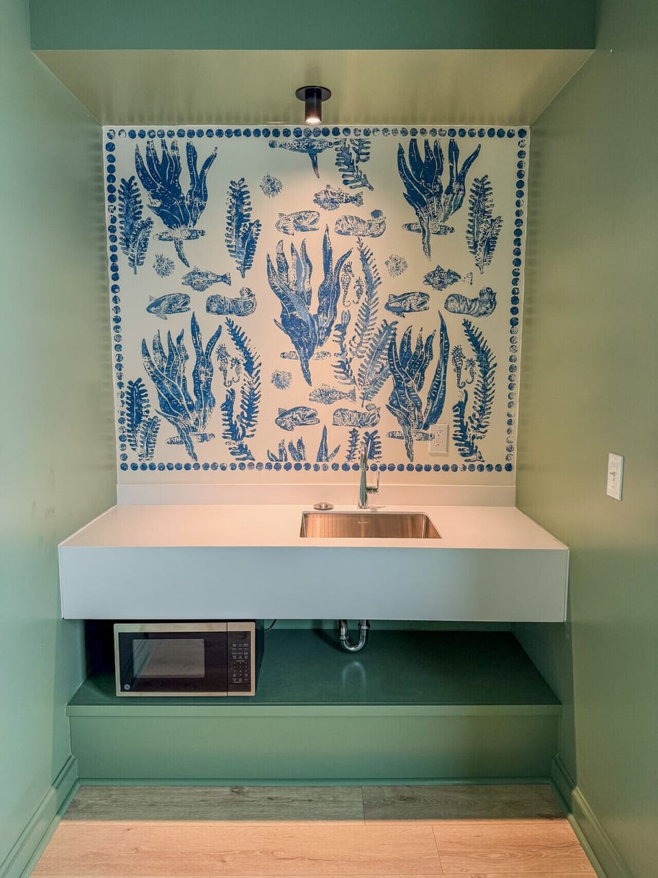 Stylish kitchenette with artistic blue detailing, stainless sink, and built-in microwave for added comfort.