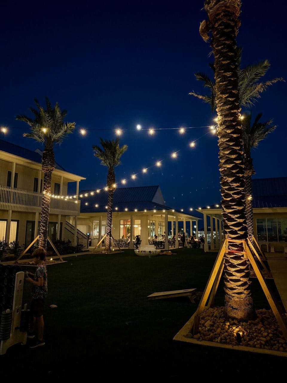 Beautifully lit courtyard featuring coastal architecture, glowing string lights, and inviting outdoor spaces at Field’s Italian.
