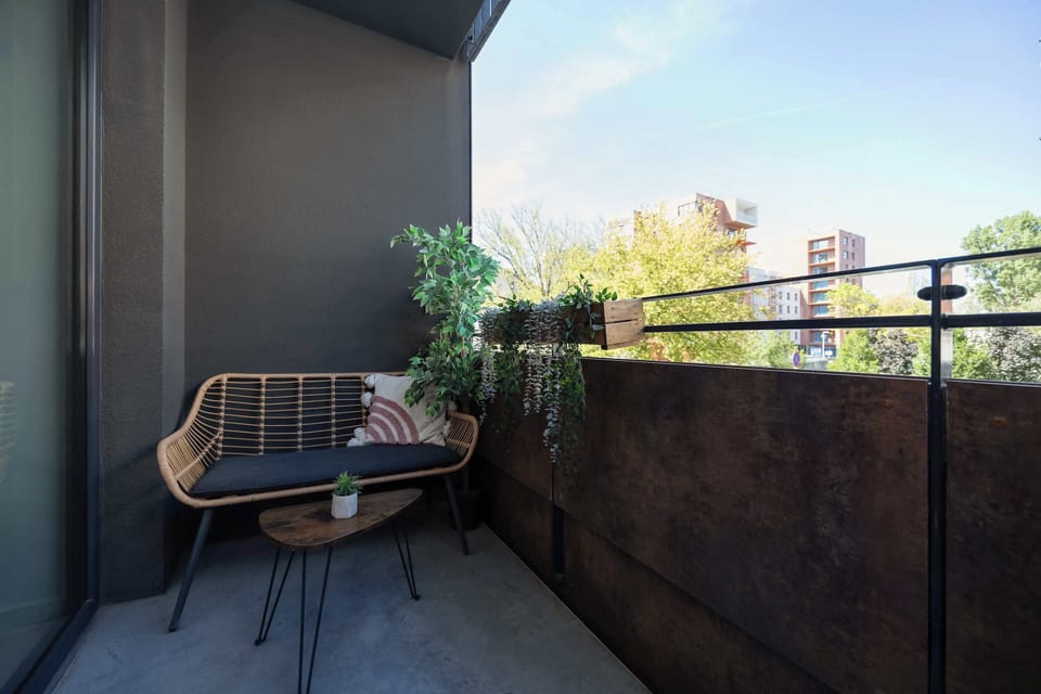 The balcony with rattan furniture and a view of greenery offers the perfect spot to enjoy a morning coffee outdoors.