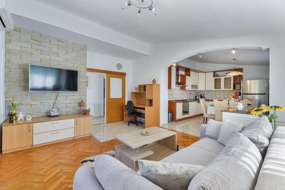 Open-plan living room with sofa, dining area, kitchen, A/C, WiFi internet, and satellite TV