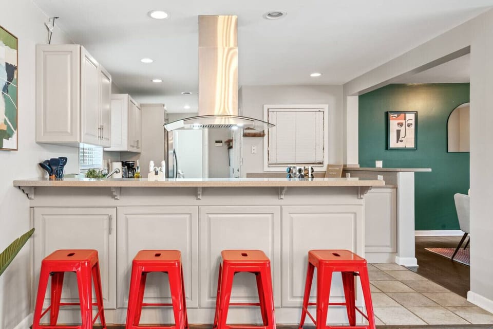 Breakfast‑bar kitchen with neutral cabinetry, stainless vent hood, and seating for four.