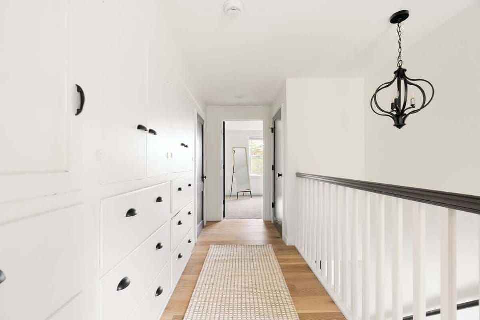 This upstairs hallway connects the bedrooms with stylish lighting and ample built-in storage for a clean, minimalist vibe.