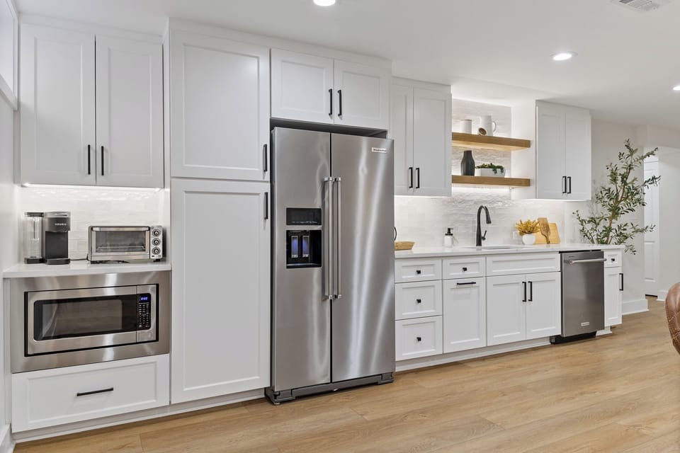 Well-equipped basement kitchenette with full-size refrigerator, microwave, sink, dishwasher, and toaster oven