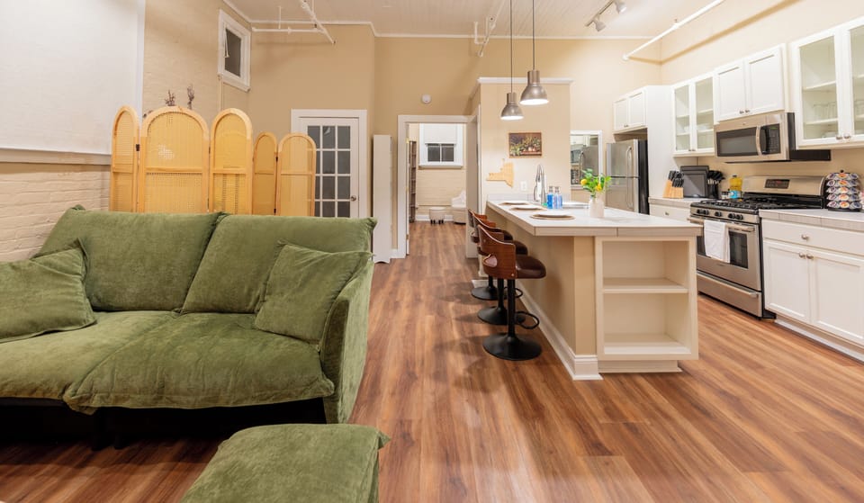 Spacious open layout with a cozy green sofa, stylish kitchen island, and inviting bar seating—perfect for cooking, relaxing, and enjoying time together.