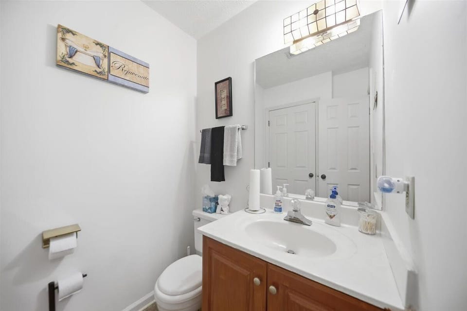 Half bathroom featuring a wood vanity, mirror, and toilet with wall art.