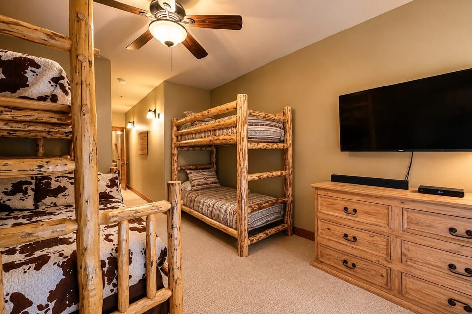 Log bunk room with two bunk beds and TV