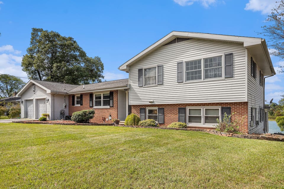 Welcome to your lakeside retreat! This spacious split-level home blends classic brick with fresh siding, giving it timeless curb appeal. The manicured lawn and inviting entryway set the stage for a relaxing stay. 