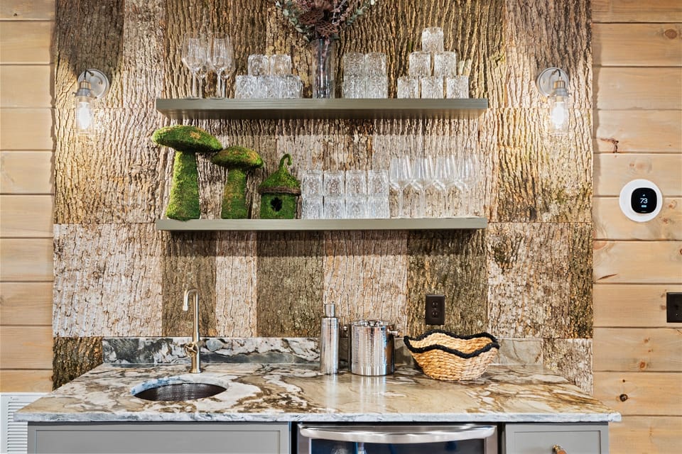 Custom wet bar with stone backsplash, beverage fridge, and glass storage—perfect for entertaining, hosting, or keeping drinks accessible for the whole group