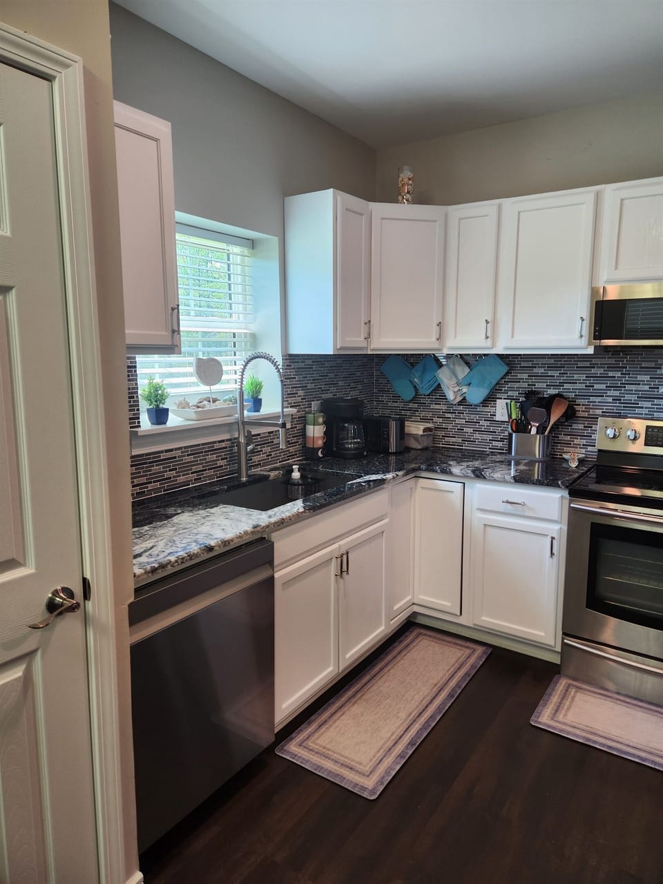 Enjoy cooking in this stylish and functional kitchen featuring crisp white cabinetry, stainless steel appliances, and a modern tile backsplash