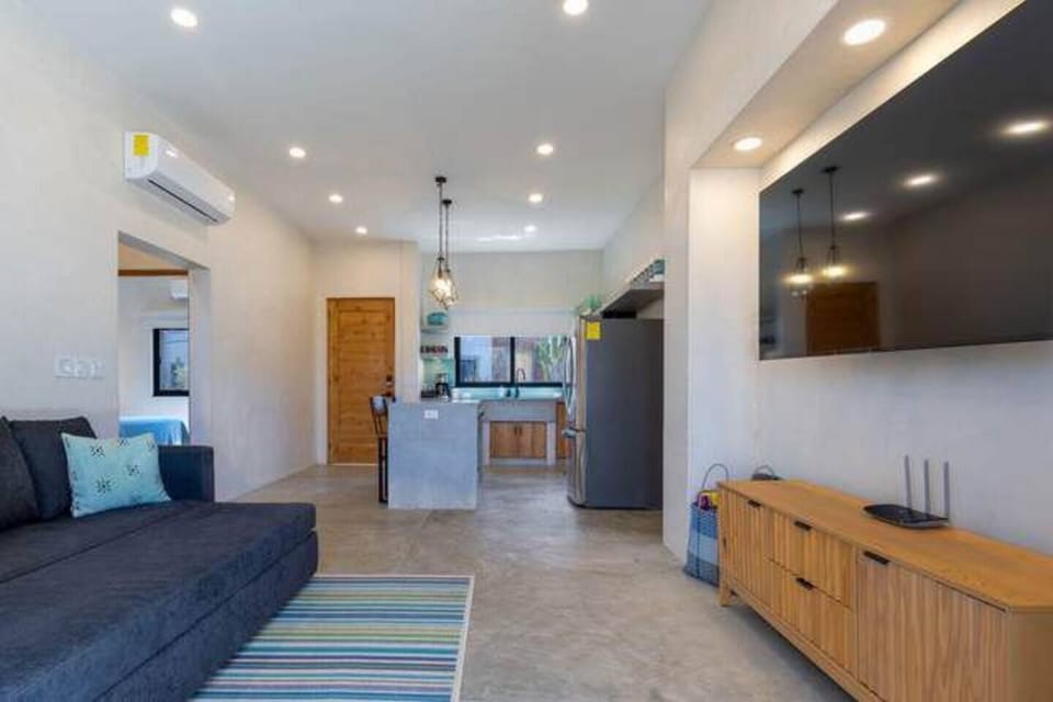 Bright, open living room with cozy seating, ceiling fan, and beachy vibes.