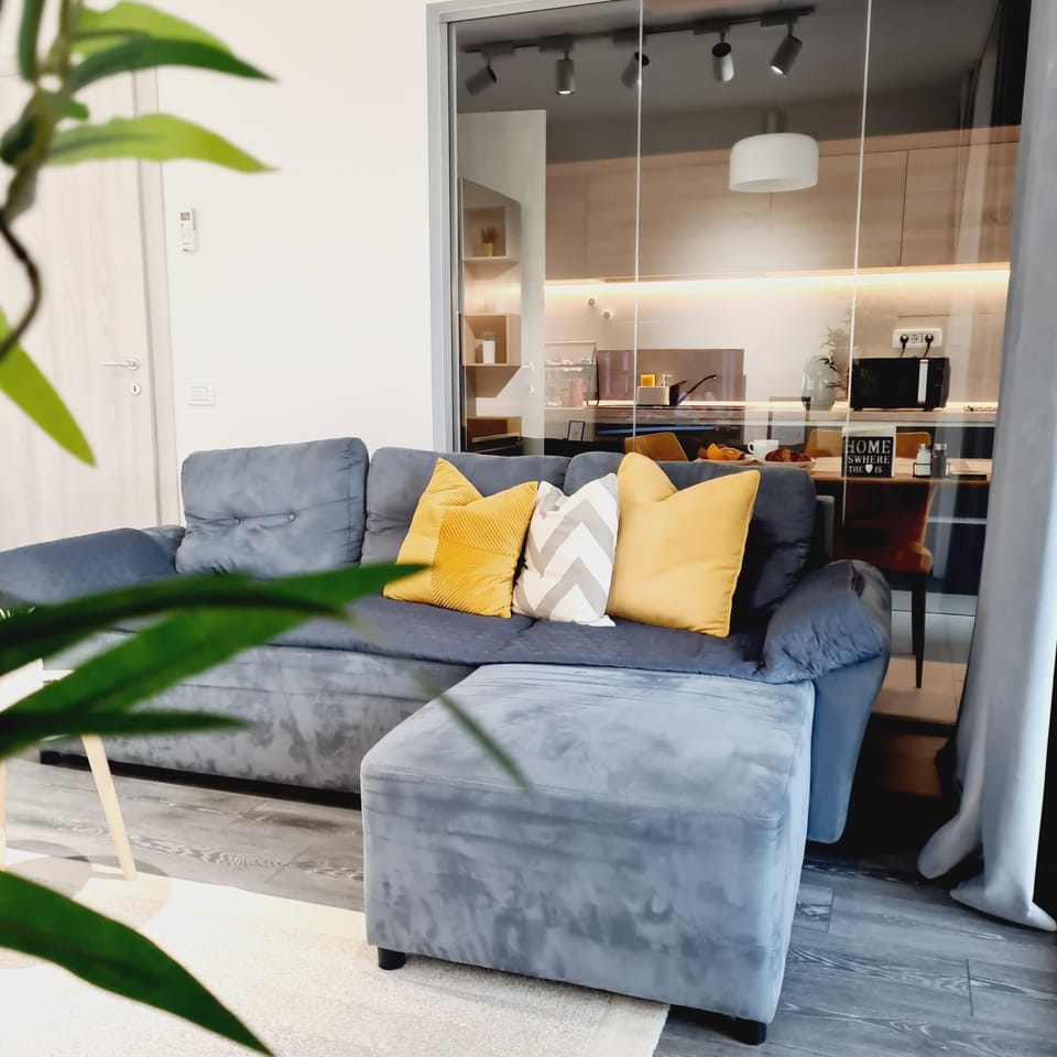 A welcoming living space with a soft sofa and warm kitchen view.

