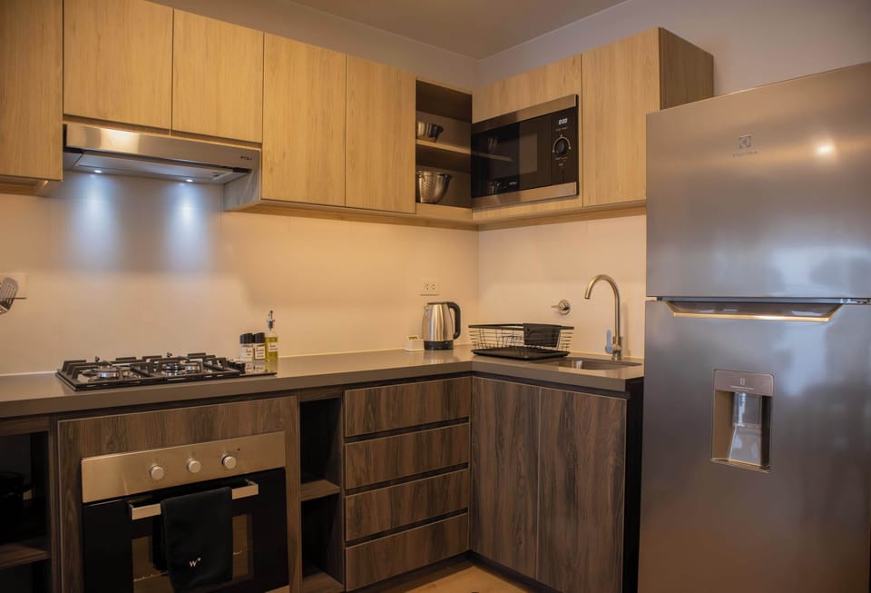 Compact kitchen with stove, oven, and sink, featuring upper and lower cabinets.