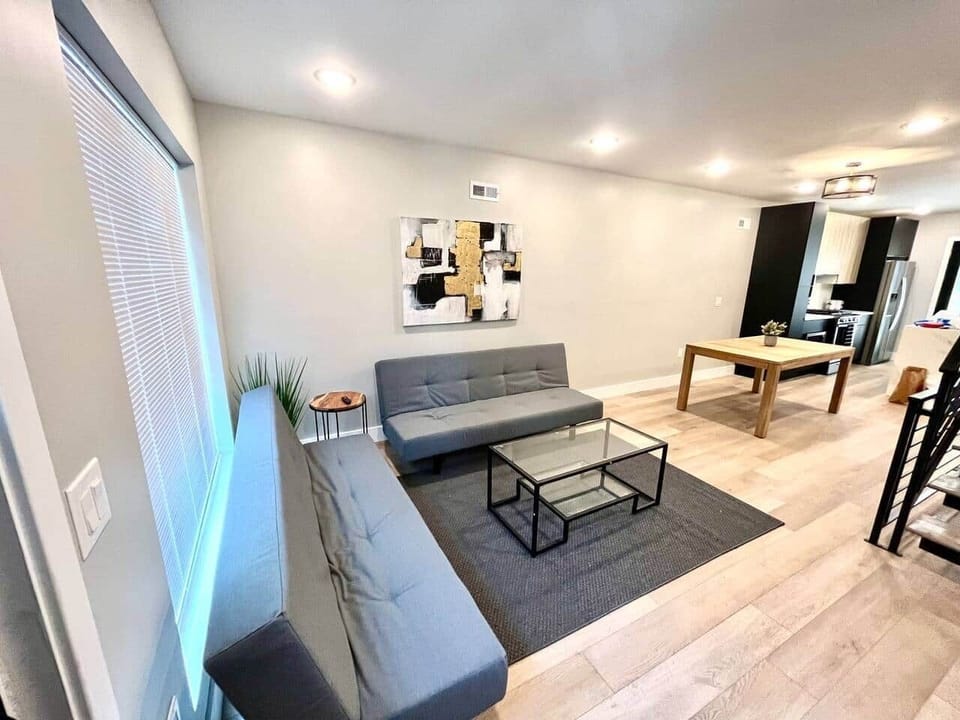 The living room, highlighted by large windows, is designed for relaxation and features a flat-screen TV along with two comfortable futon sofa beds to accommodate additional guests.