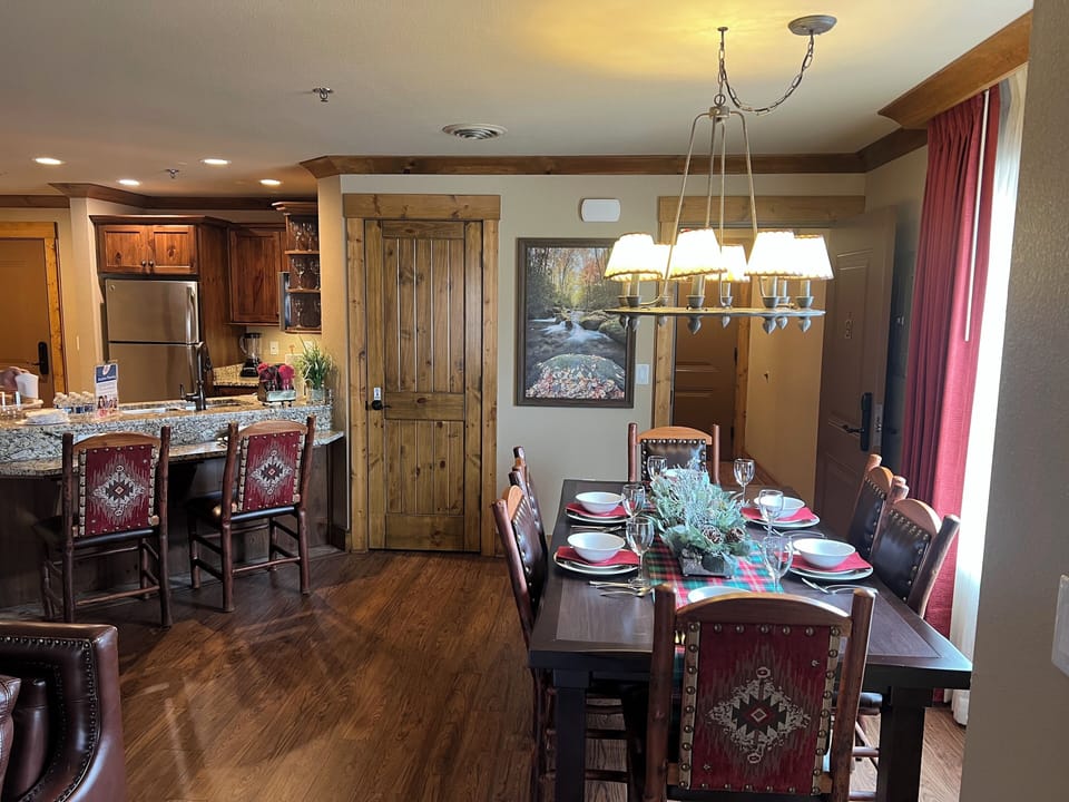 This photo of dining area and kitchen is set in the model condo. with plates set