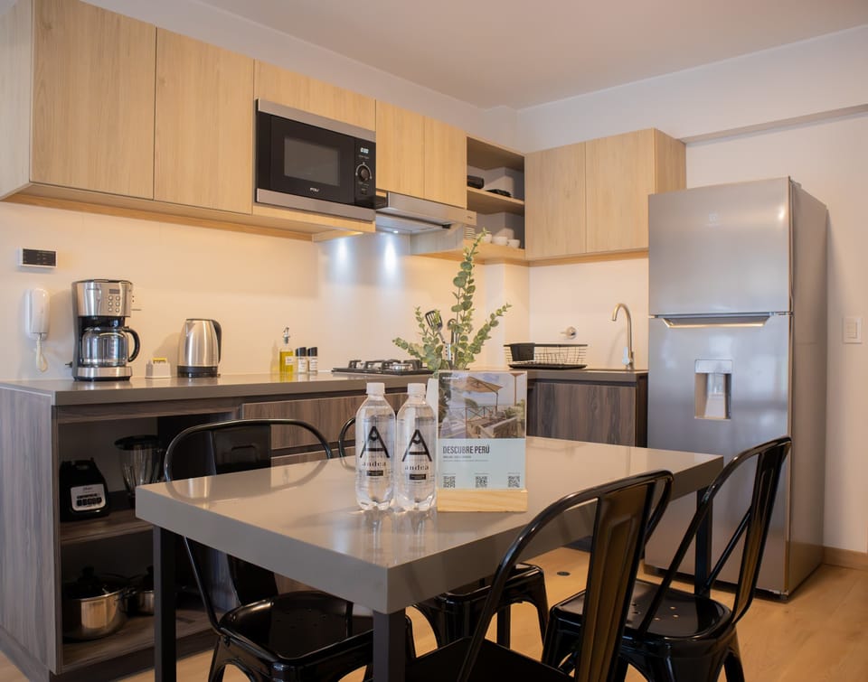 Kitchen and dining area with wooden cabinets, refrigerator, and black chairs.