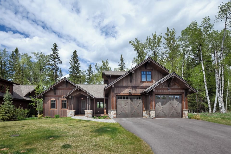 Arrive to a striking lodge-style home nestled among tall trees.