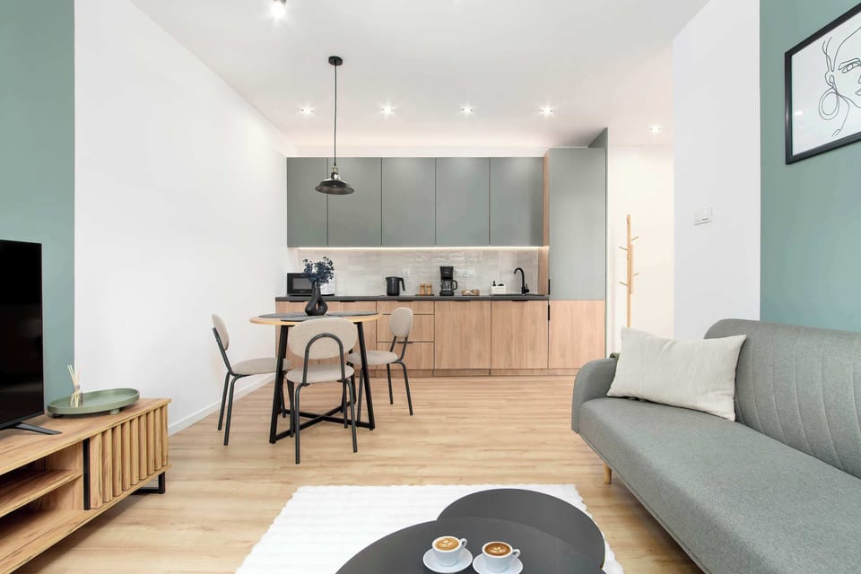 Another view of the living and kitchen area with the sofa and coffee table. The space is bright and inviting, perfect for relaxation.