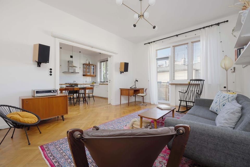 A spacious living room with light curtains and comfortable armchairs offers the perfect conditions for watching TV or relaxing together.