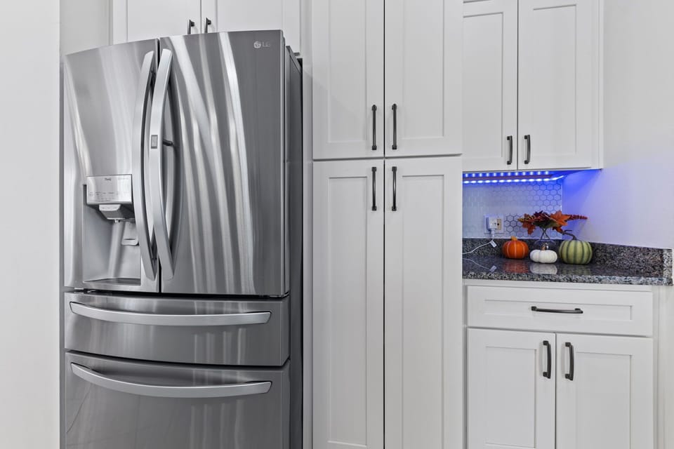 Modern kitchen with refrigerator, ice maker, water dispenser, and full cooking essentials.