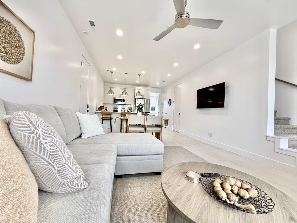 The living room is furnished with a comfortable couch, Smart TV, ceiling fan, and plenty of natural light.